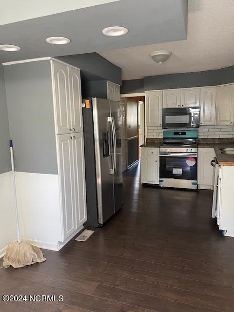 kitchen featuring sink, dark wood-type flooring, stainless steel appliances, white cabinets, and decorative backsplash