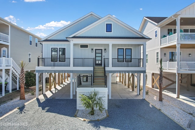 coastal home featuring board and batten siding, a carport, gravel driveway, and covered porch