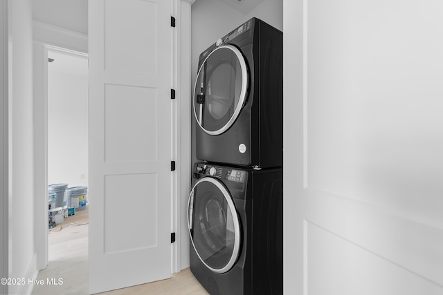 laundry room with laundry area, stacked washer and dryer, and light wood-style floors