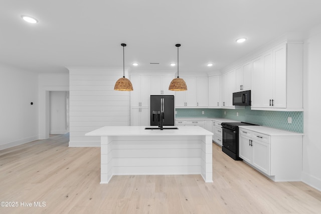 kitchen featuring white cabinets, black appliances, and light countertops