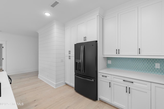 kitchen featuring visible vents, white cabinetry, black fridge with ice dispenser, and light countertops