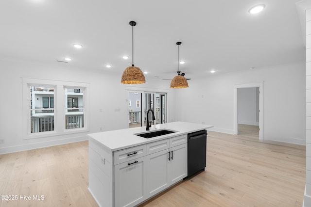 kitchen featuring a sink, light countertops, light wood-style floors, pendant lighting, and dishwasher