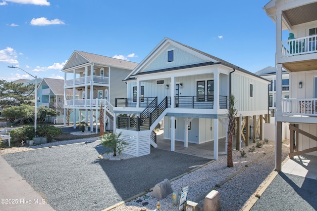 coastal home featuring stairway, driveway, covered porch, a carport, and board and batten siding