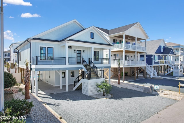 coastal inspired home featuring a carport, stairway, covered porch, and driveway