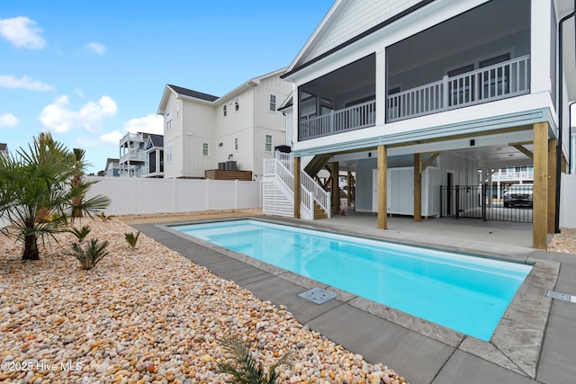 view of swimming pool featuring a fenced in pool, fence, stairs, a sunroom, and a patio area