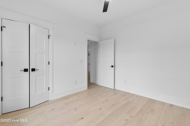 unfurnished bedroom with light wood-style flooring, a ceiling fan, and baseboards