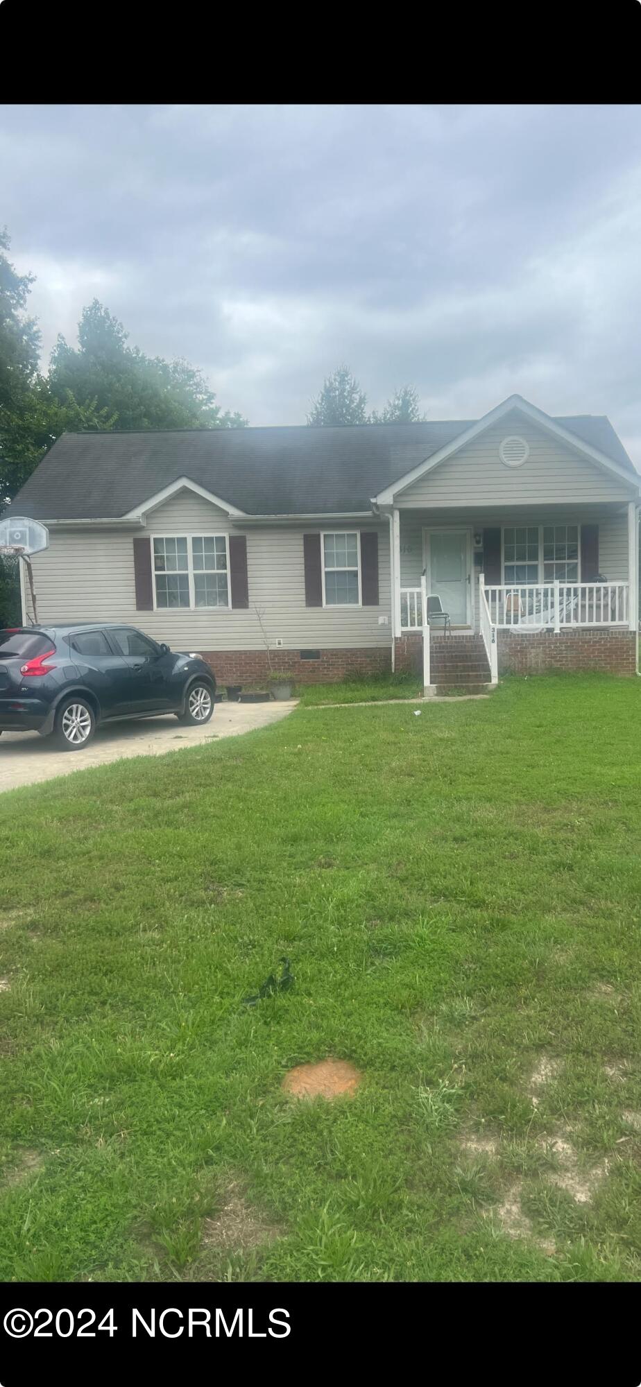 single story home featuring covered porch and a front lawn