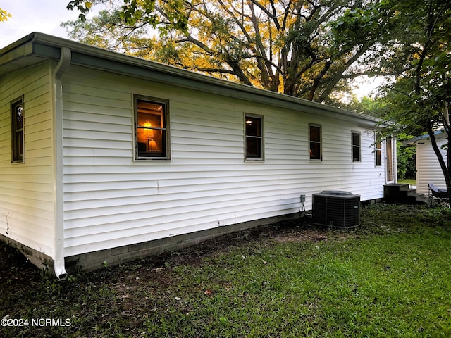 view of side of home featuring central air condition unit and a lawn