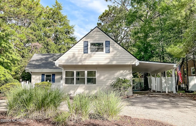 view of front of house featuring driveway, an attached carport, and fence