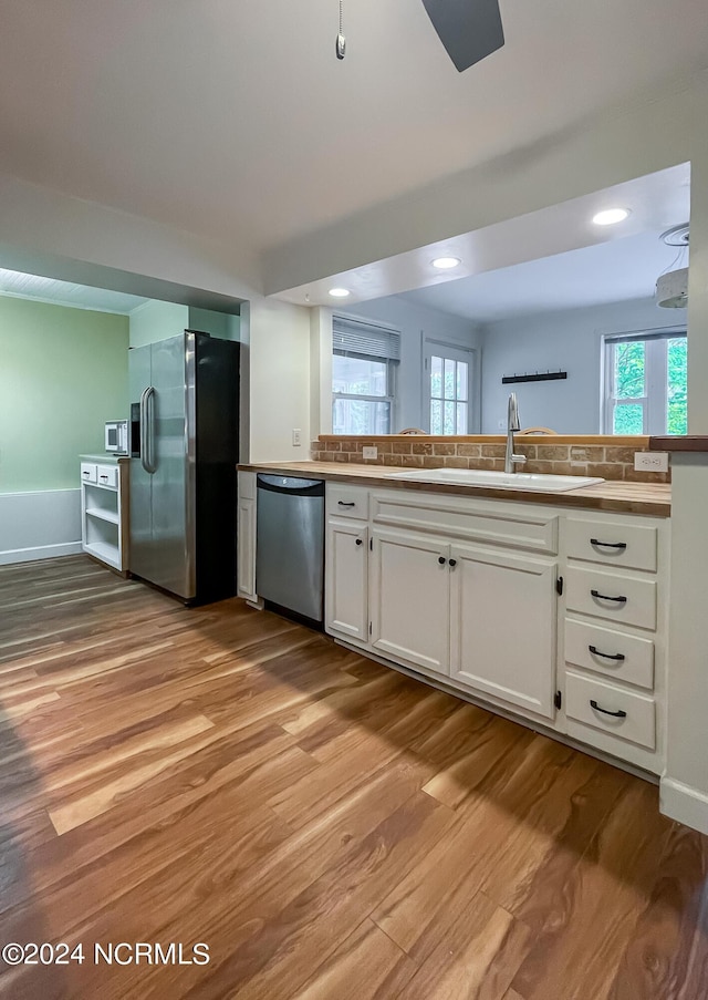 kitchen featuring light wood finished floors, recessed lighting, appliances with stainless steel finishes, white cabinetry, and a sink