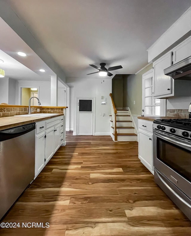 kitchen featuring wood finished floors, a sink, white cabinets, appliances with stainless steel finishes, and decorative backsplash