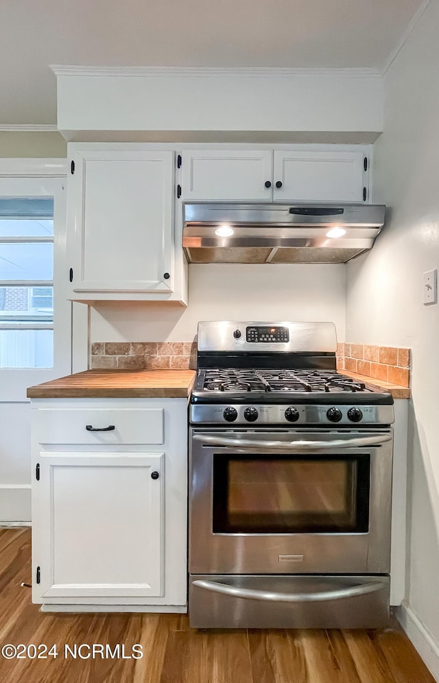 kitchen with ornamental molding, under cabinet range hood, white cabinets, and stainless steel gas range oven