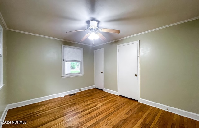 unfurnished bedroom featuring crown molding, visible vents, ceiling fan, wood finished floors, and baseboards