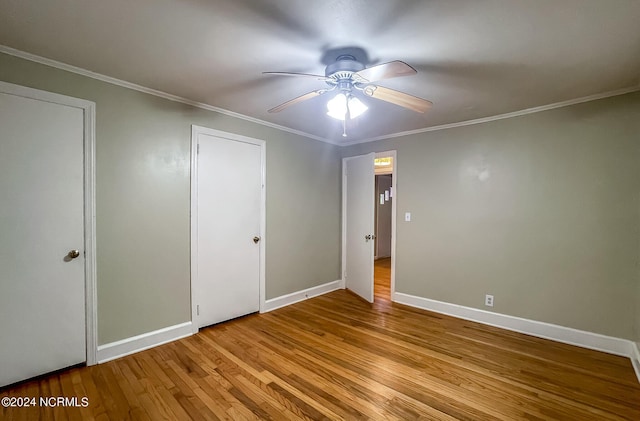 unfurnished bedroom featuring a ceiling fan, crown molding, baseboards, and wood finished floors