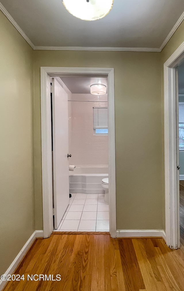 hallway featuring ornamental molding, wood finished floors, and baseboards