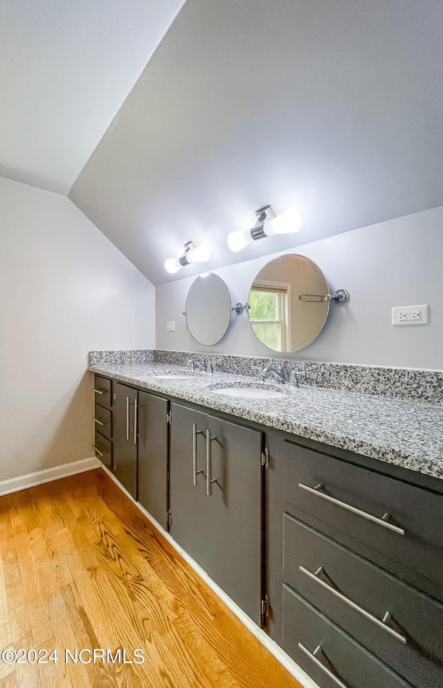 bathroom featuring lofted ceiling, vanity, baseboards, and wood finished floors