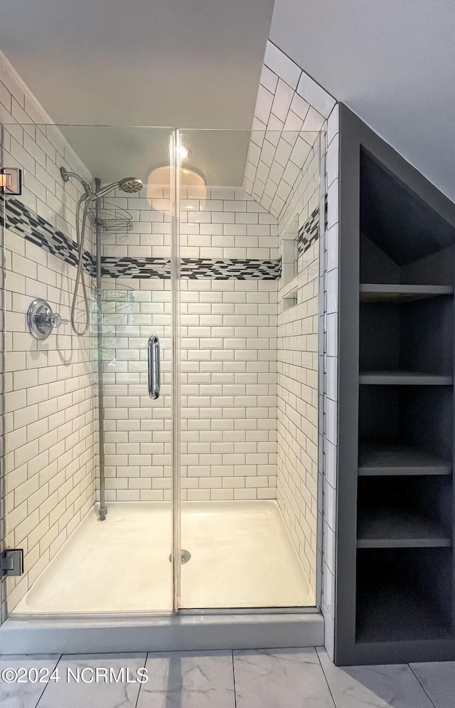 bathroom with vaulted ceiling, marble finish floor, and a shower stall