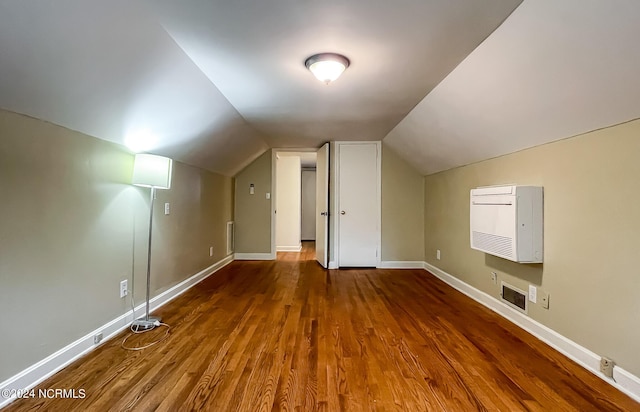 additional living space featuring baseboards, visible vents, vaulted ceiling, and wood finished floors