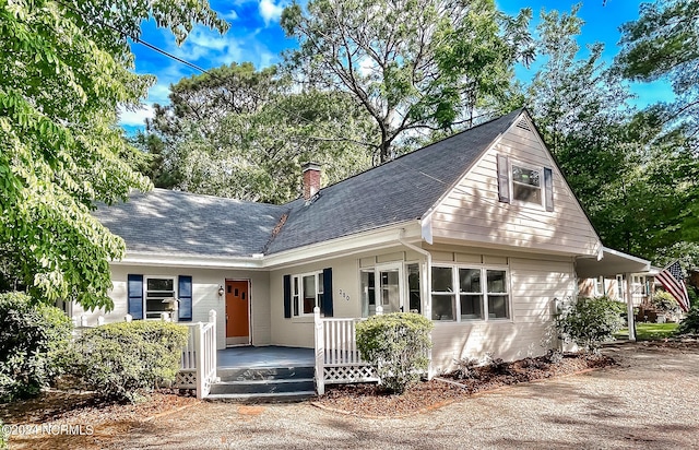 view of front of house featuring a chimney, a porch, and roof with shingles