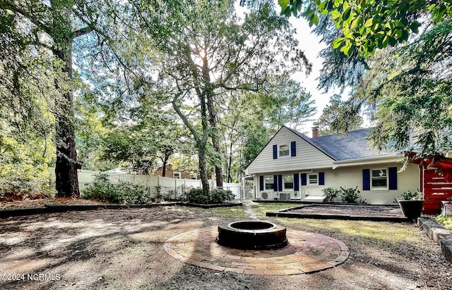 rear view of house with an outdoor fire pit, a chimney, and fence