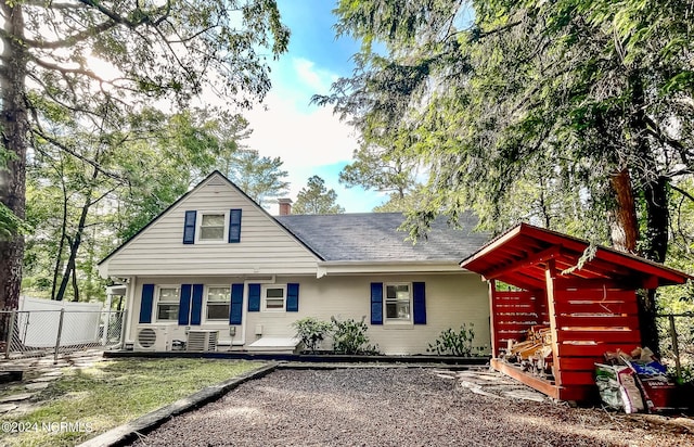 view of front of home with a chimney, roof with shingles, fence, ac unit, and a front yard