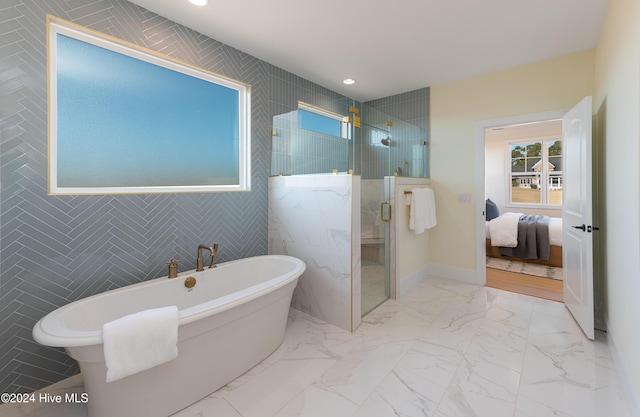 bathroom with shower with separate bathtub and tile walls