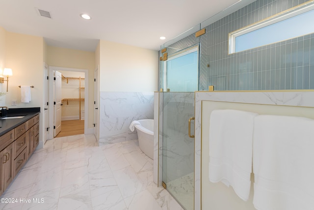 bathroom with vanity, separate shower and tub, and tile walls