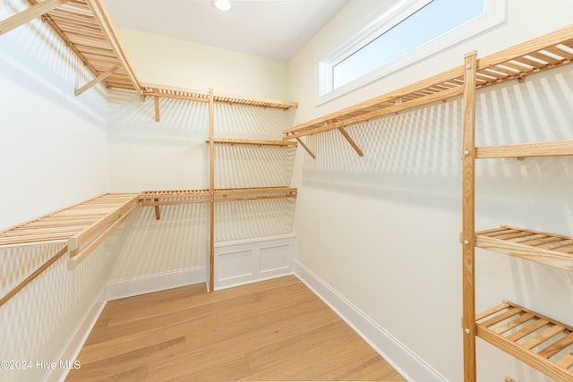 walk in closet with light hardwood / wood-style floors