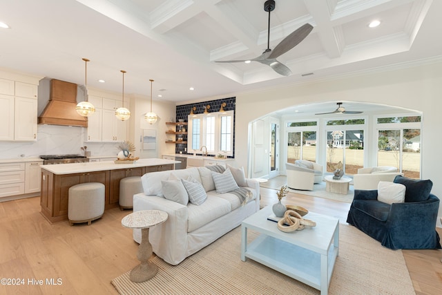 living room featuring beam ceiling, ceiling fan, sink, light hardwood / wood-style flooring, and crown molding