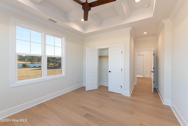 unfurnished bedroom featuring coffered ceiling, light hardwood / wood-style flooring, ornamental molding, beamed ceiling, and a closet