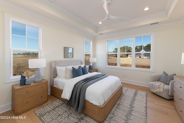 bedroom with a raised ceiling, ceiling fan, light hardwood / wood-style floors, and ornamental molding