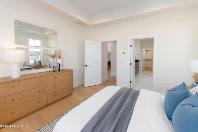 bedroom featuring a raised ceiling, light wood-type flooring, and ornamental molding