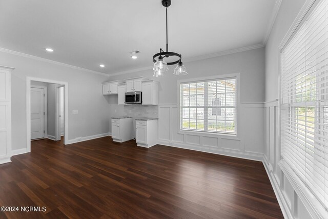 unfurnished living room featuring ornamental molding, dark hardwood / wood-style floors, and a chandelier