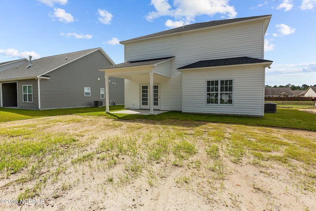 back of house with central air condition unit, a lawn, and french doors