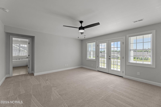 unfurnished bedroom featuring french doors, access to outside, ensuite bath, light colored carpet, and ceiling fan