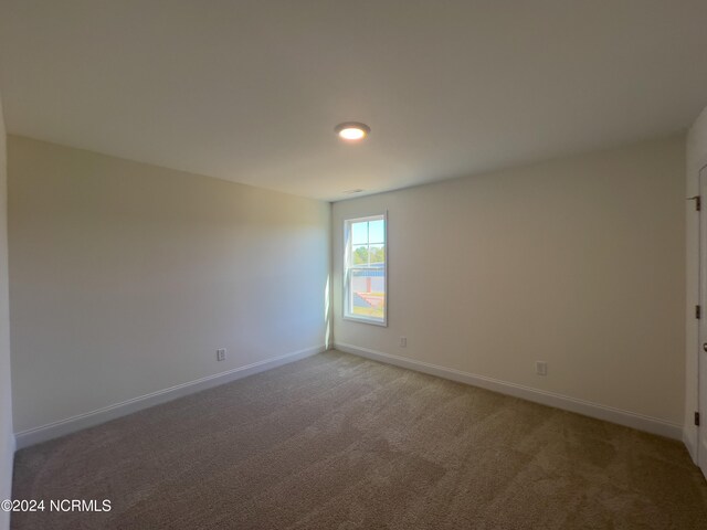 empty room with dark colored carpet and a water view