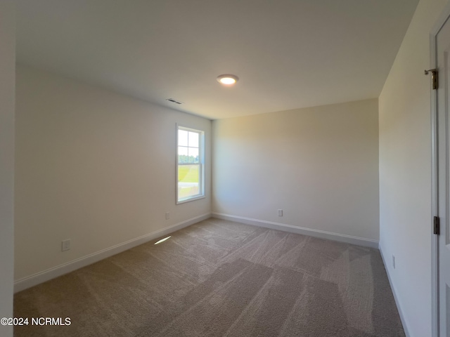 carpeted spare room featuring visible vents and baseboards