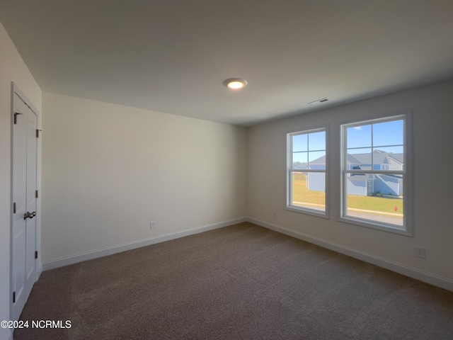 empty room featuring visible vents, carpet flooring, and baseboards