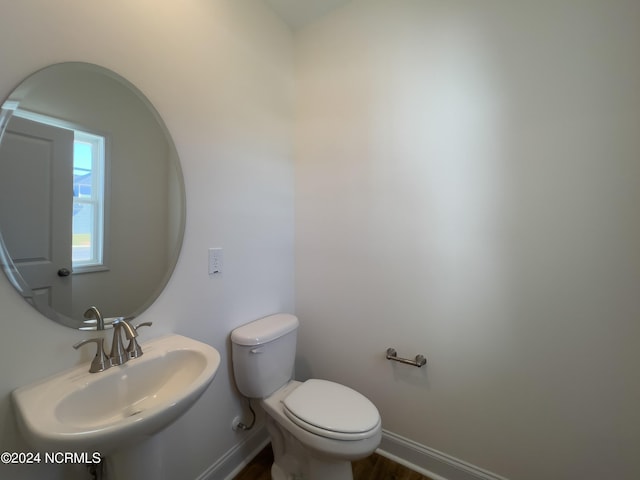 bathroom featuring wood finished floors, toilet, baseboards, and a sink