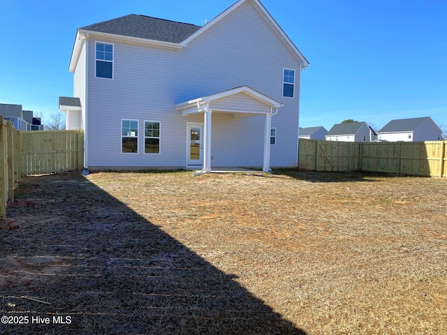 back of house featuring a lawn and a fenced backyard