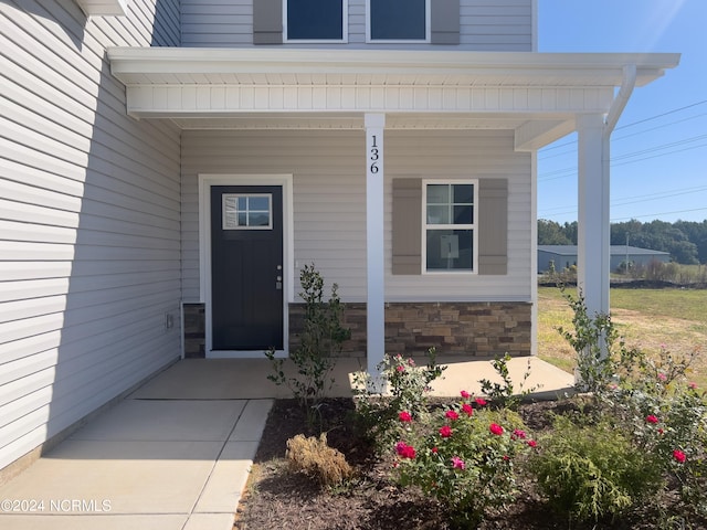 doorway to property with stone siding and covered porch
