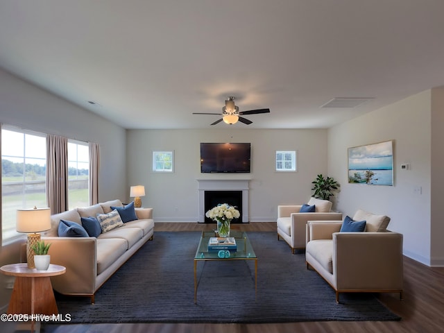 living area with baseboards, a ceiling fan, wood finished floors, and visible vents