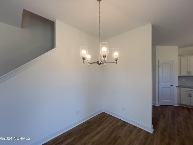 unfurnished dining area with an inviting chandelier, dark wood-style flooring, and baseboards