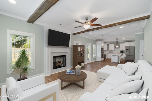 living room with light hardwood / wood-style floors, ceiling fan, beam ceiling, and ornamental molding