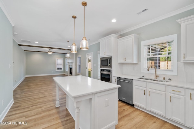 kitchen with stainless steel appliances, a kitchen island, sink, ceiling fan, and white cabinets