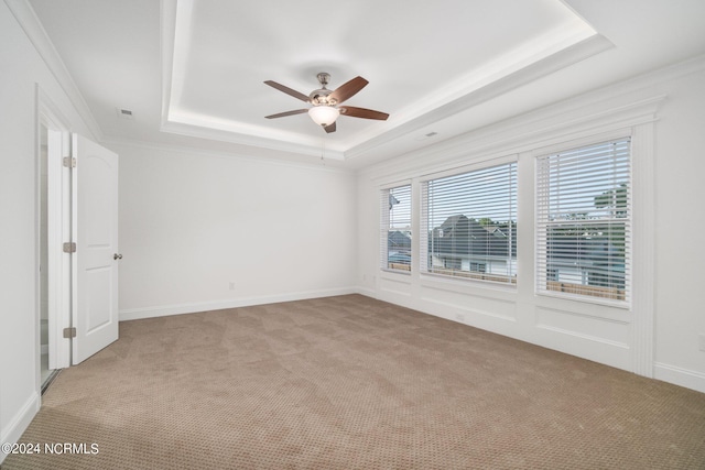 carpeted spare room featuring ceiling fan, a raised ceiling, and ornamental molding