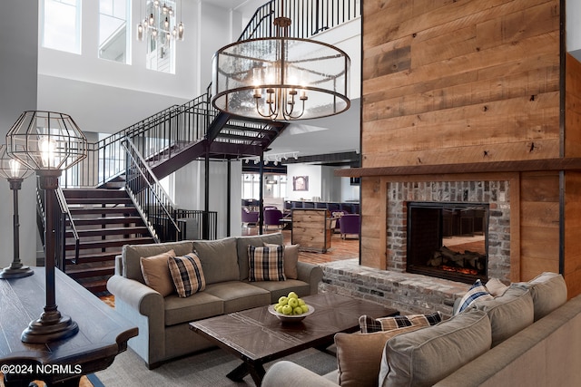 living room with a high ceiling, a notable chandelier, a brick fireplace, and wooden walls