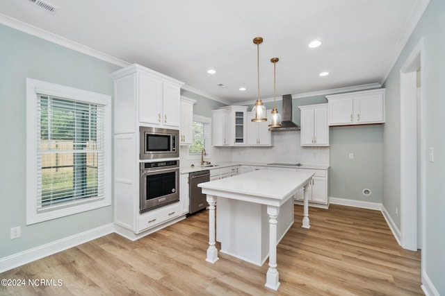 kitchen with light wood-type flooring, appliances with stainless steel finishes, wall chimney range hood, a breakfast bar area, and a kitchen island