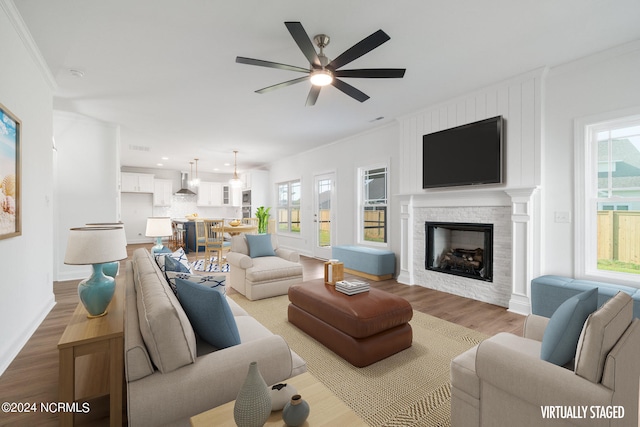 living room with crown molding, a wealth of natural light, light wood-type flooring, and a fireplace