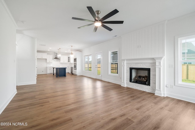 unfurnished living room with a healthy amount of sunlight, ornamental molding, and hardwood / wood-style floors